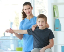 A physiotherapist guiding a boy through an arm stretch